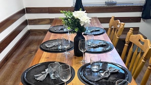 A dining table set with black plates, silverware, and wine glasses, centered with a vase of white flowers. - Vineyard cottage Ranč pri Hanzeku (Videm)