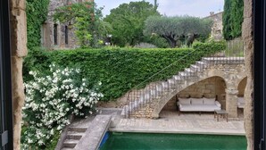 A stone staircase leading to a white outdoor seating area with a pool in the background. - LUXURY CHATEAU FOR RENT UZES PROVENCE (Saint-Maximin)