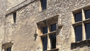 A stone building with multiple windows and an arched doorway. - LUXURY CHATEAU FOR RENT UZES PROVENCE (Saint-Maximin)