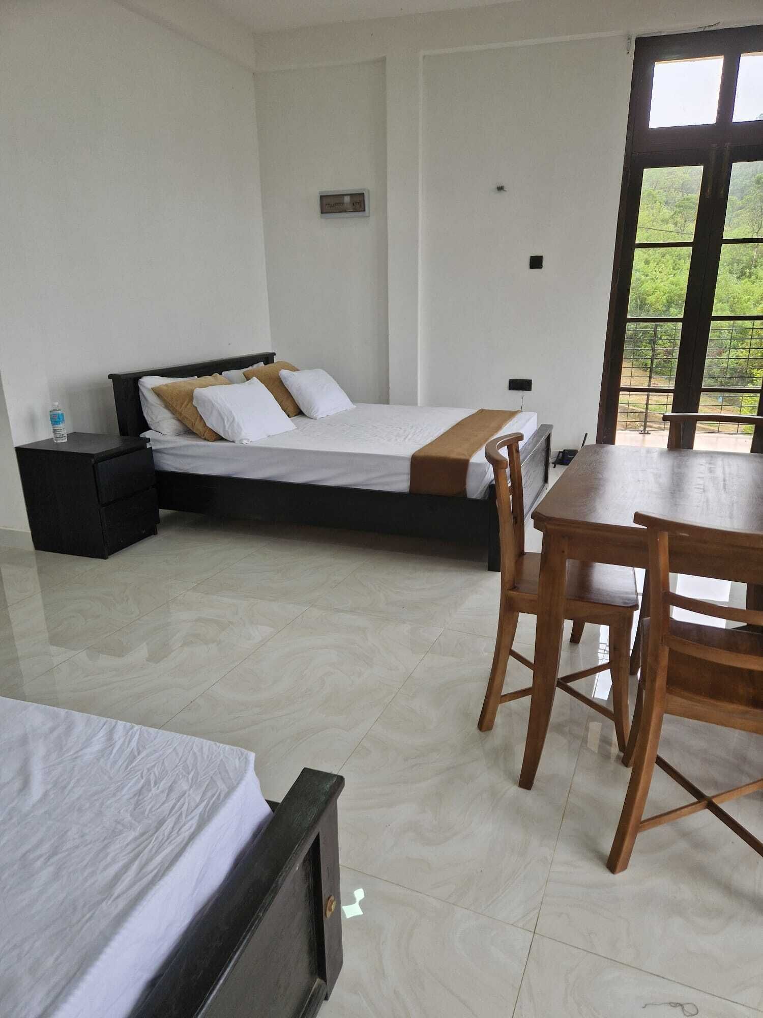 Camera d'albergo con un letto, una scrivania e una sedia. Si vede del verde attraverso la finestra.