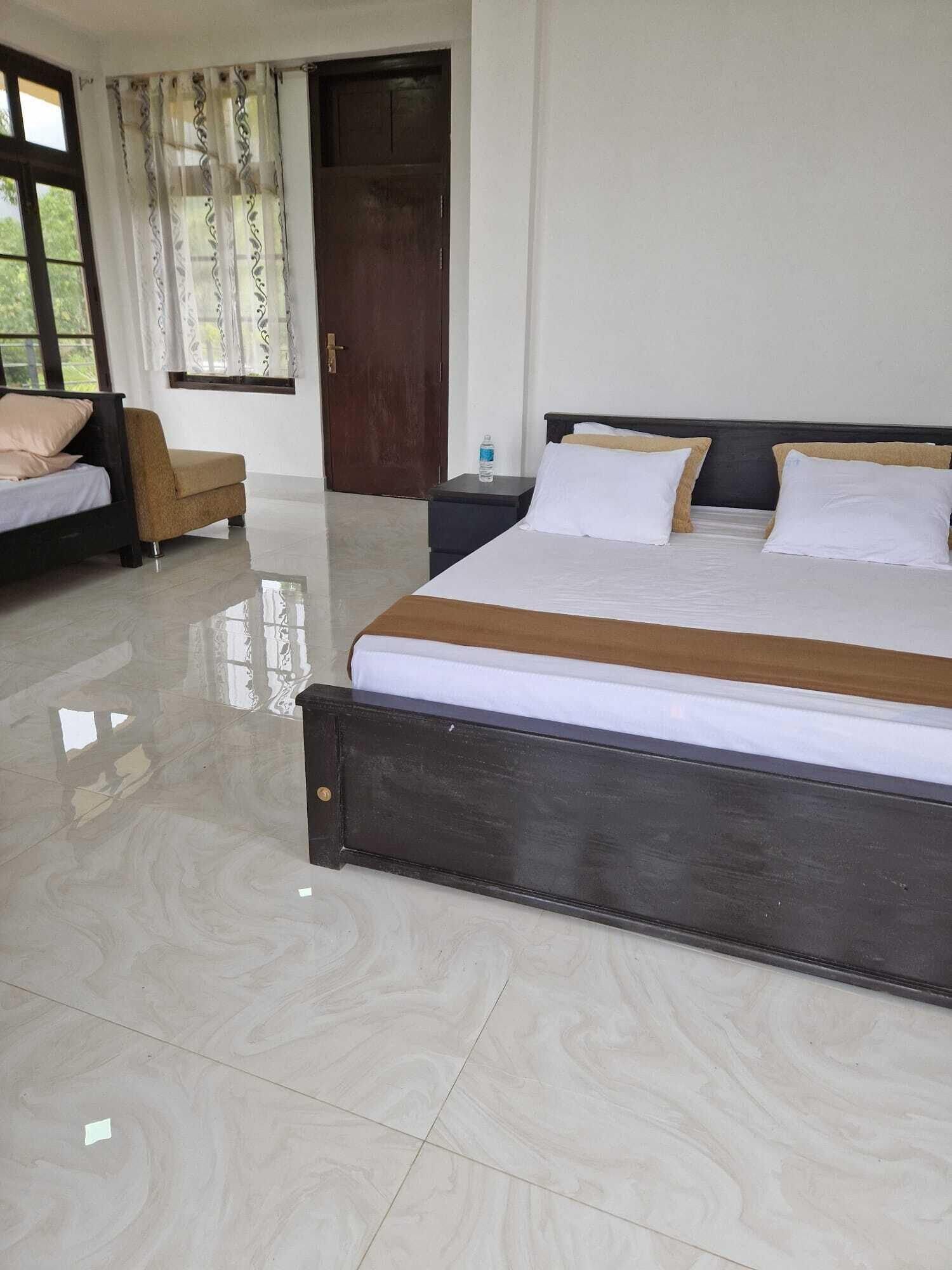 A hotel room with a large bed, a smaller bed, a chair, a nightstand, and a door.