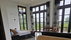 Una habitación de hotel moderna con una cama grande, un sofá y un comedor con vistas al exterior.