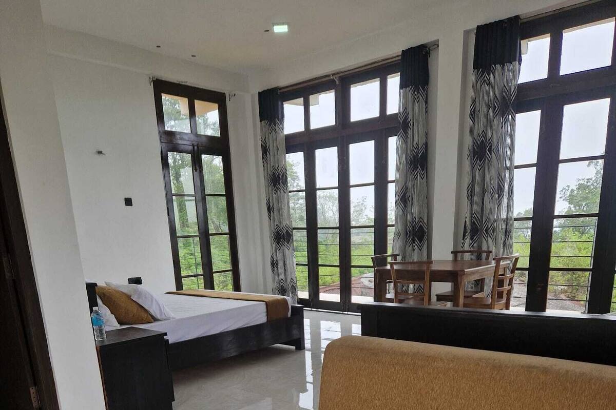 Una habitación de hotel moderna con una cama grande, un sofá y un comedor con vistas al exterior.