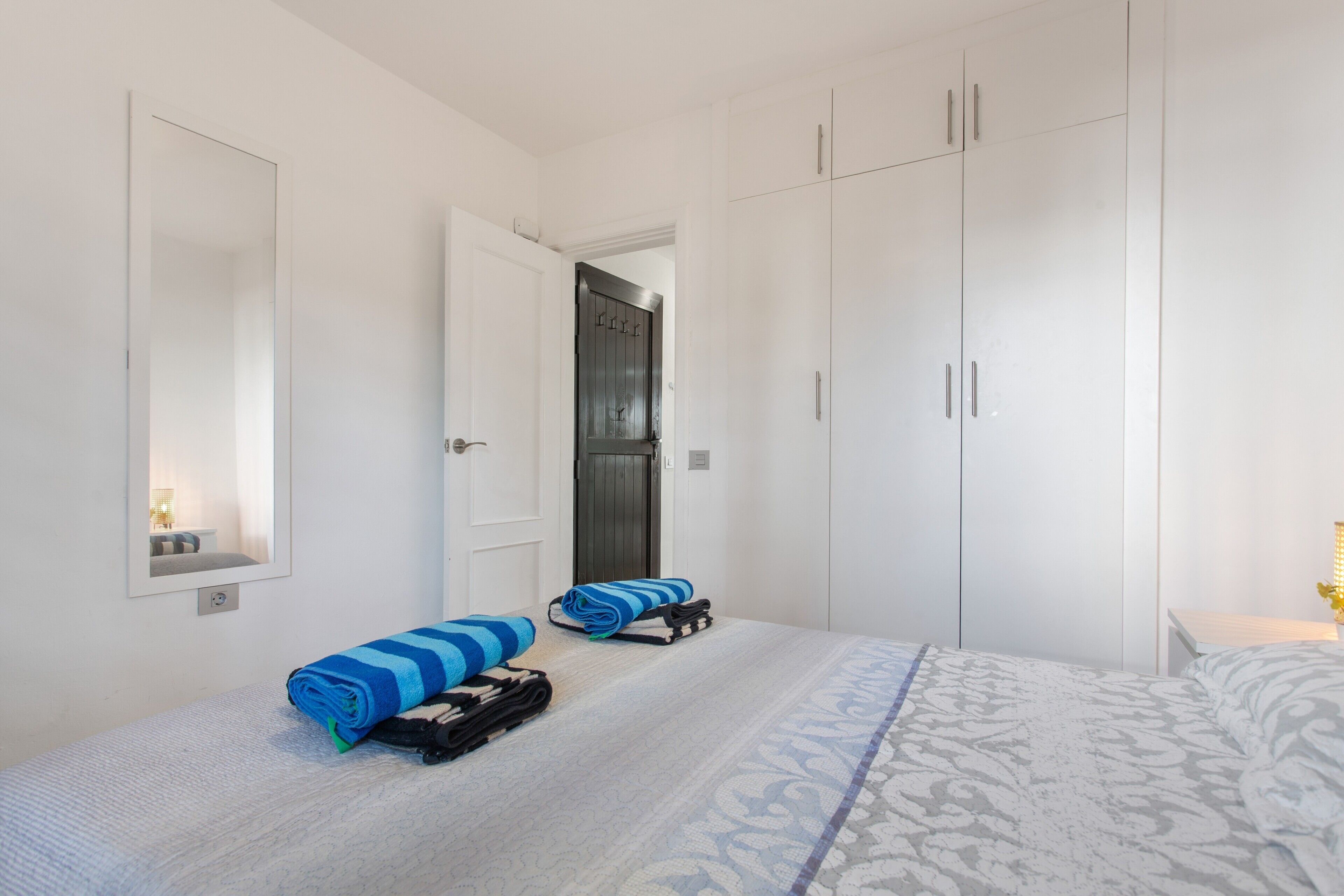 Une chambre d’hôtel avec un lit, une armoire, un miroir et une porte.