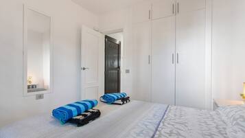 A hotel room with a bed, a wardrobe, a mirror, and a door.