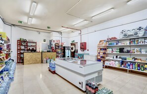 Un magasin bien éclairé, avec des étagères remplies de divers produits, un espace central pour exposer les articles et une signalétique claire indiquant les sorties.