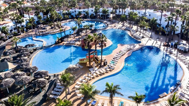 A resort with multiple swimming pools, palm trees, and lounge areas. - Coral Bliss Apartment with Shared Pool, Private Terrace, and Wi-Fi (Corralejo)