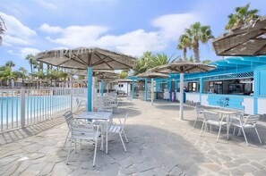 A poolside area with outdoor seating and umbrellas, a bar, and a pool.