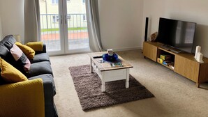 A living room with a sofa, a coffee table, a TV, and a sliding glass door to the outside.