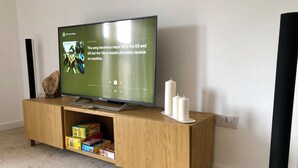 A flat-screen TV on a wooden stand with a shelf below displaying children's toys.
