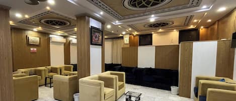 Eine Hotelhalle mit beigefarbenen Sofas, einem Marmorboden und dekorativen Deckenmustern.