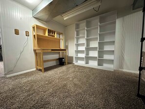 Una habitación con literas, suelo cubierto de alfombra, paredes blancas y estanterías empotradas.