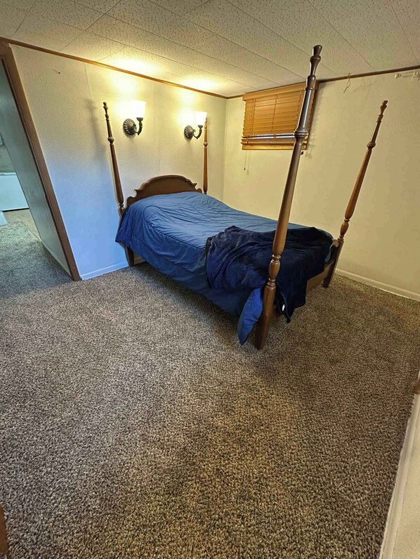 Un dormitorio con cama con dosel, suelo alfombrado y dos lámparas de pared.