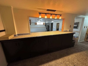 Una cucina con un piano di lavoro scuro, uno schienale decorato e un lampadario a soffitto.