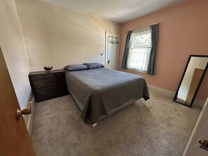 Une chambre à coucher avec un lit, une commode, une fenêtre et un miroir.
