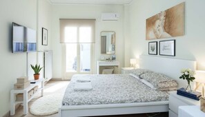 Ein modernes Schlafzimmer mit einem großen Bett, Nachttischen, einem Schminktisch und Bildern an den Wänden.