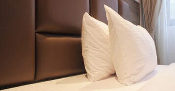 Una cama de hotel con almohadas blancas y un cabecero marrón.