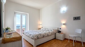 A bedroom with a bed, bedside tables, a chair, a nightstand, a lamp, a wall-mounted control panel, and a view of the outdoors. - Casa Rinascita with Private Pool (Nulvi)