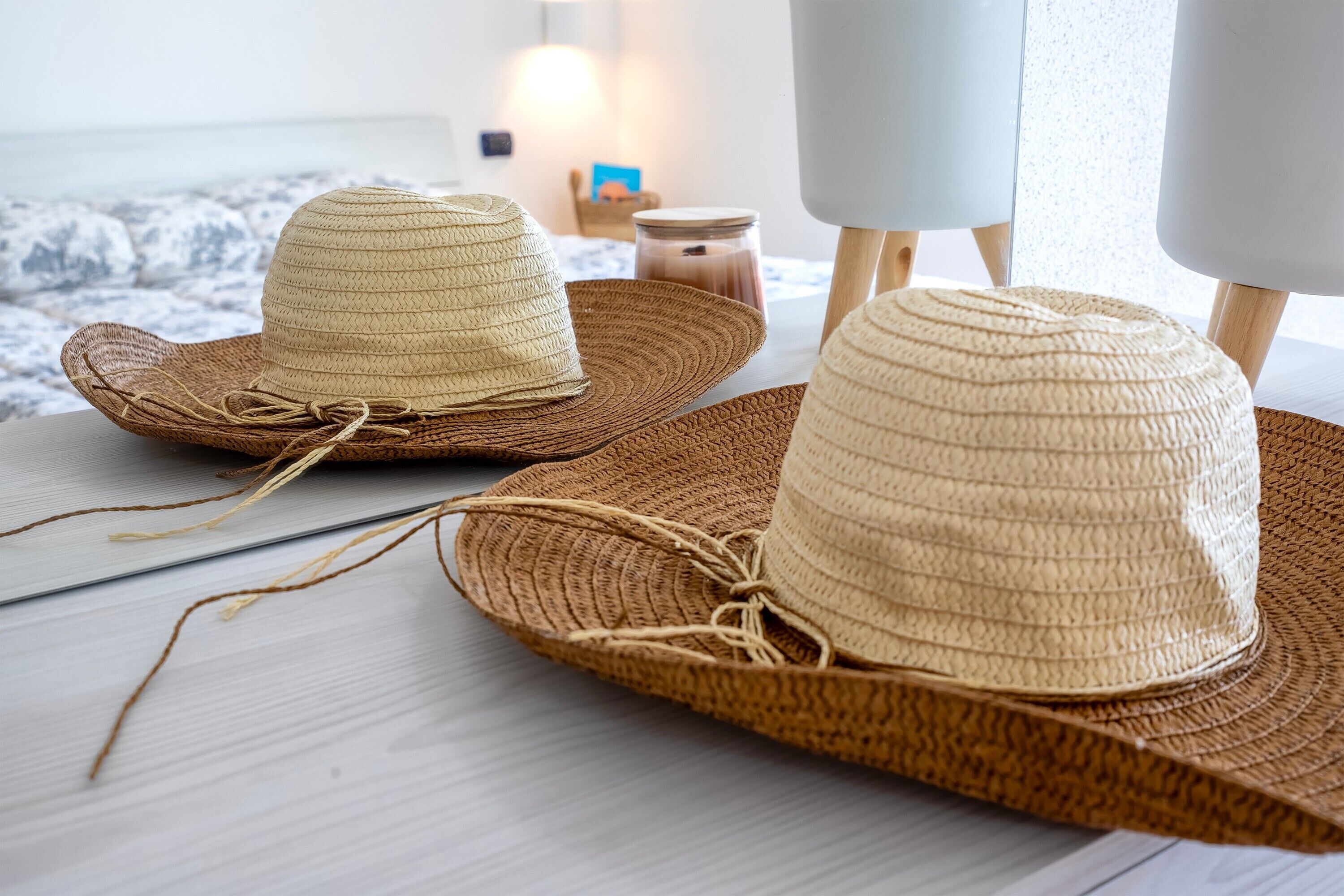 Two straw hats on a wooden table with a view of the ocean.