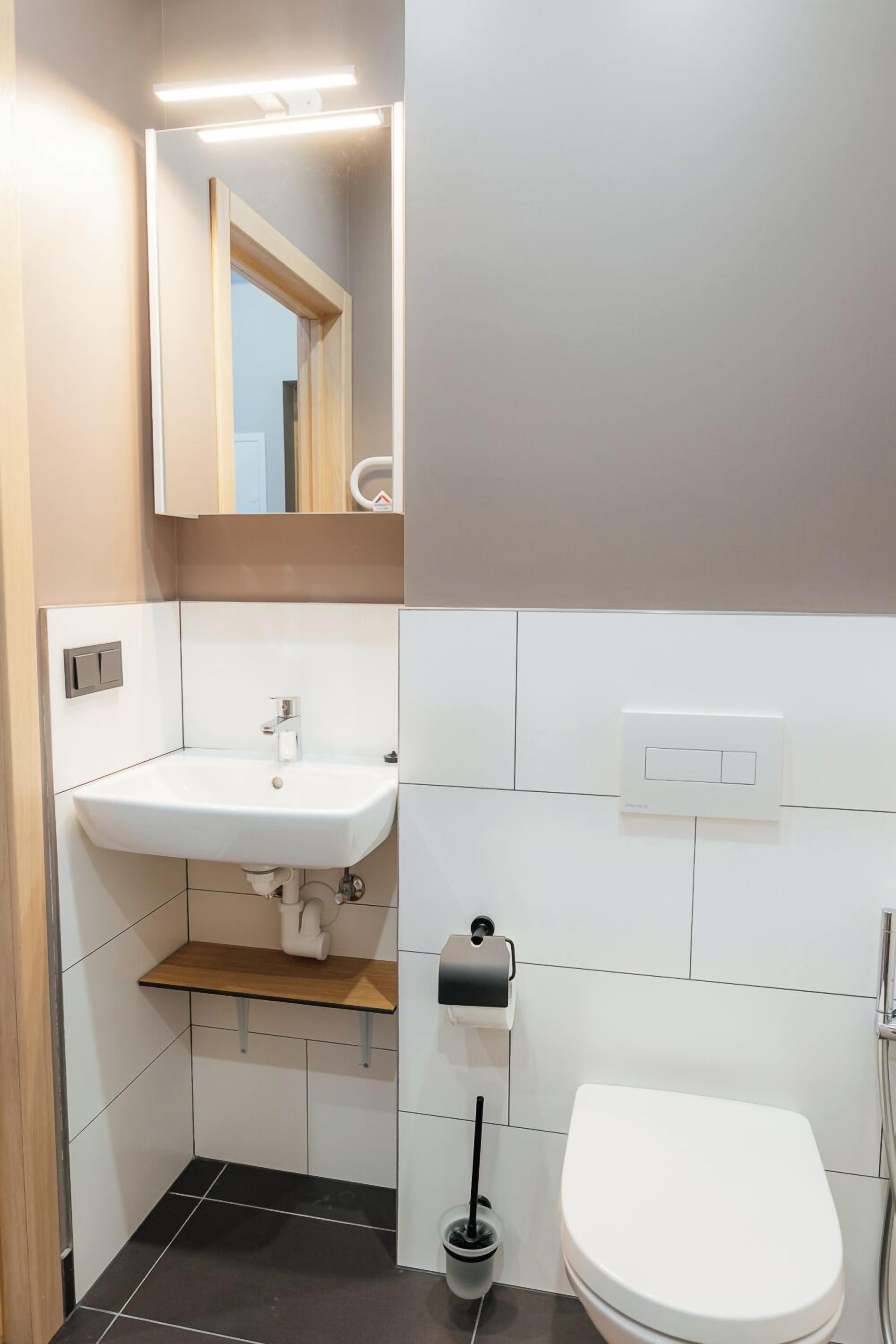 A bathroom with a white sink, mirror, toilet, and a towel rack.