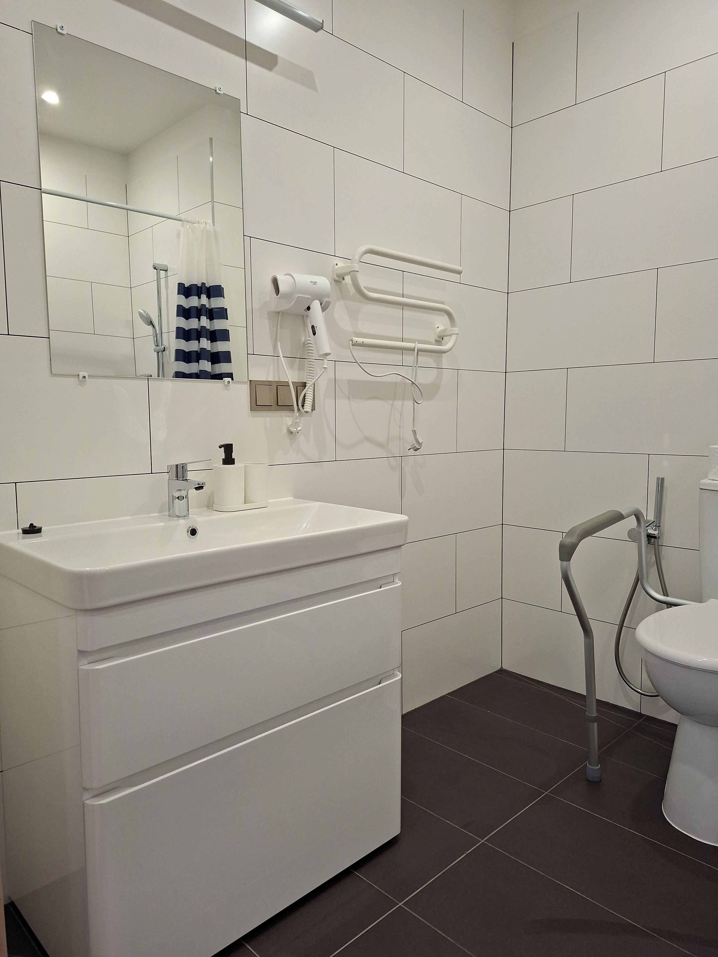 Une salle de bain moderne avec un meuble-lavabo blanc, un miroir, un porte-serviettes et des toilettes.