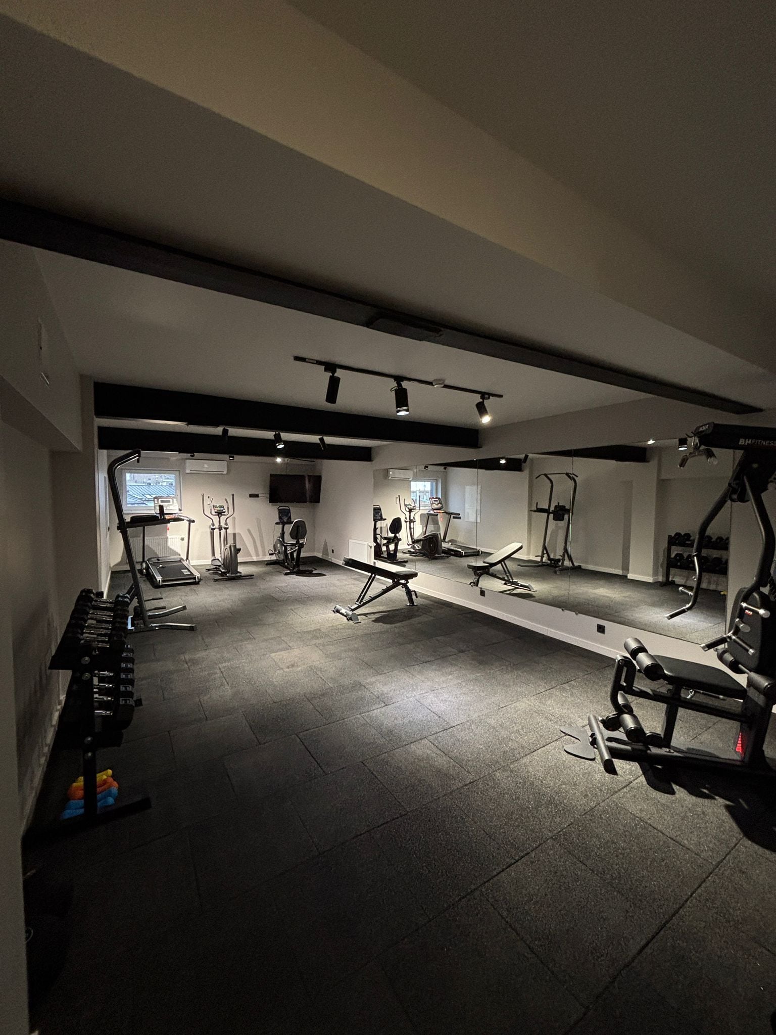 A gym with various exercise equipment, including treadmills, weight machines, and free weights.