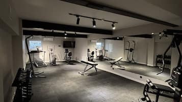 A gym with various exercise equipment, including treadmills, weight machines, and free weights.