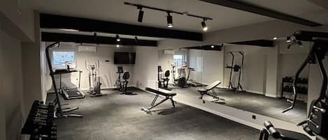 A gym with various exercise equipment, including treadmills, weight machines, and free weights.