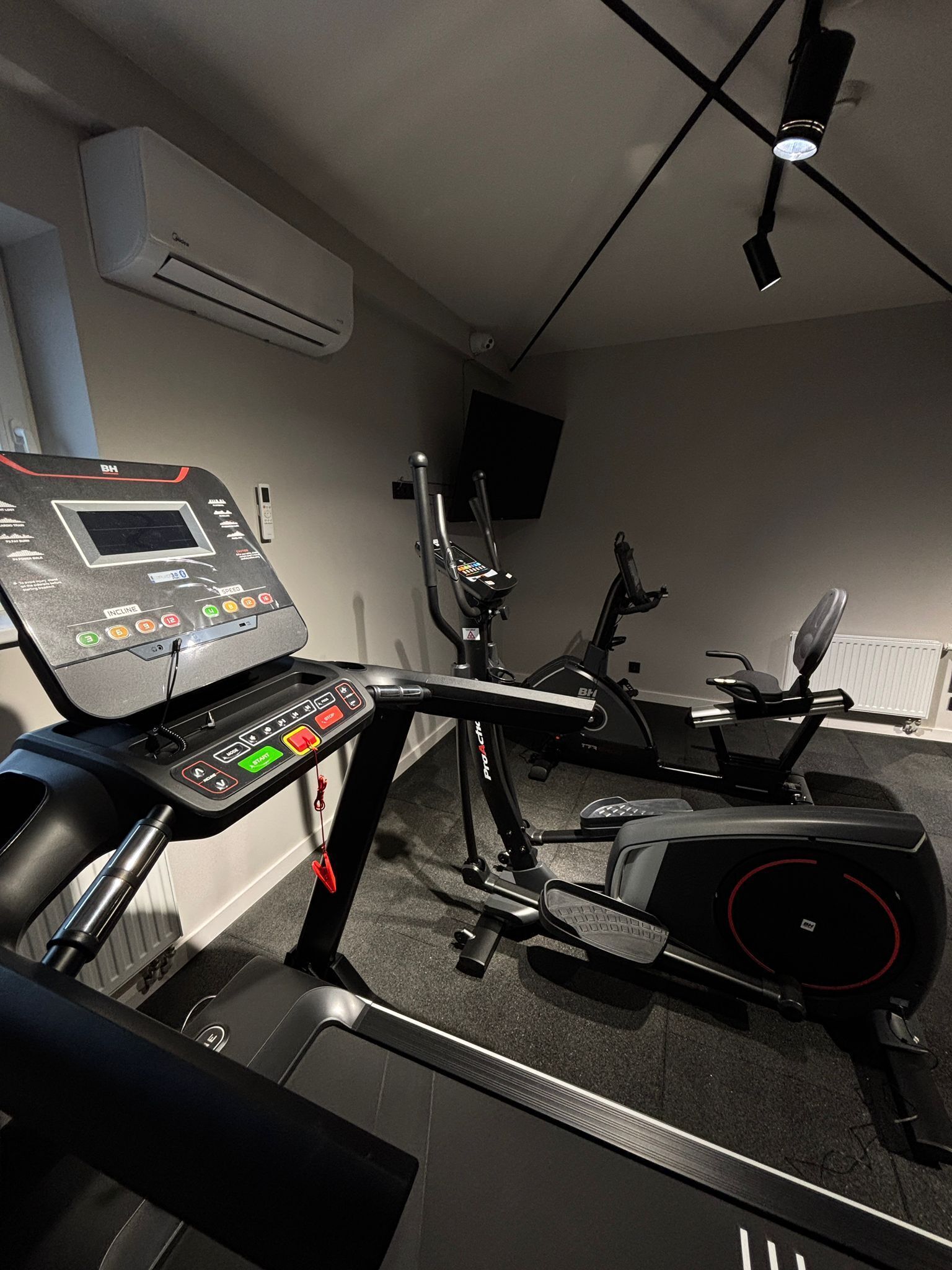 A home gym with a stationary bike, elliptical, and treadmill.