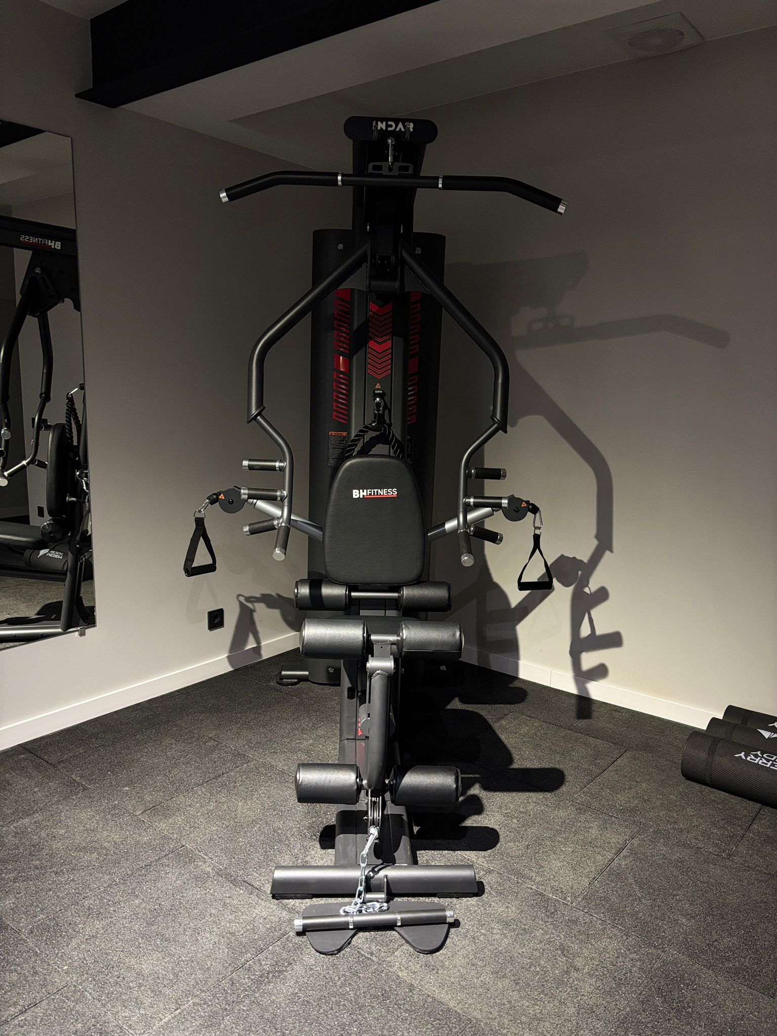 Una palestra con una sbarra per trazioni, una panca per pesi e diverse attrezzature per esercizi.