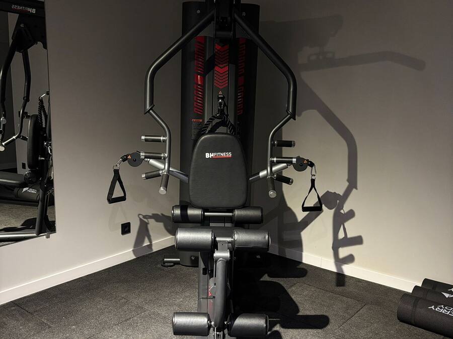 Una palestra con una sbarra per trazioni, una panca per pesi e diverse attrezzature per esercizi.