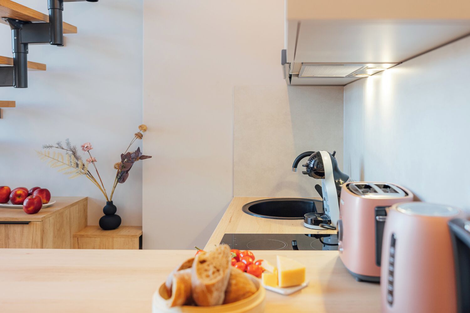 Een moderne keuken met een houten aanrecht, een spoelbak, een broodrooster en een vaas met gedroogde bloemen.