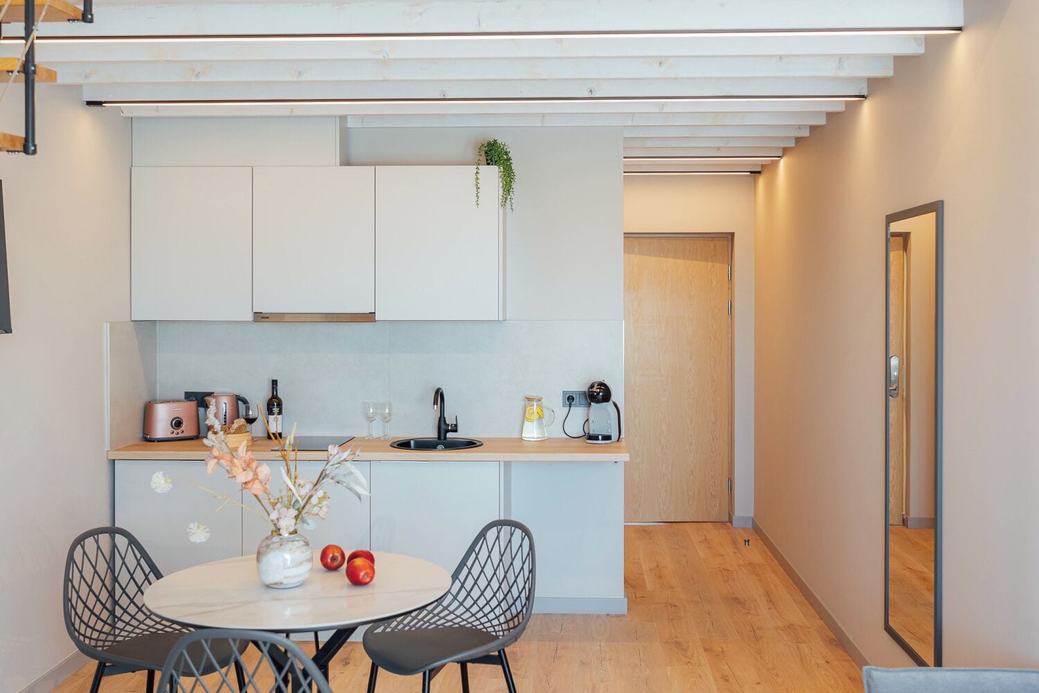 Una cucina moderna con mobili bianchi, un piano di lavoro in legno e un'area pranzo con due sedie e un tavolo.