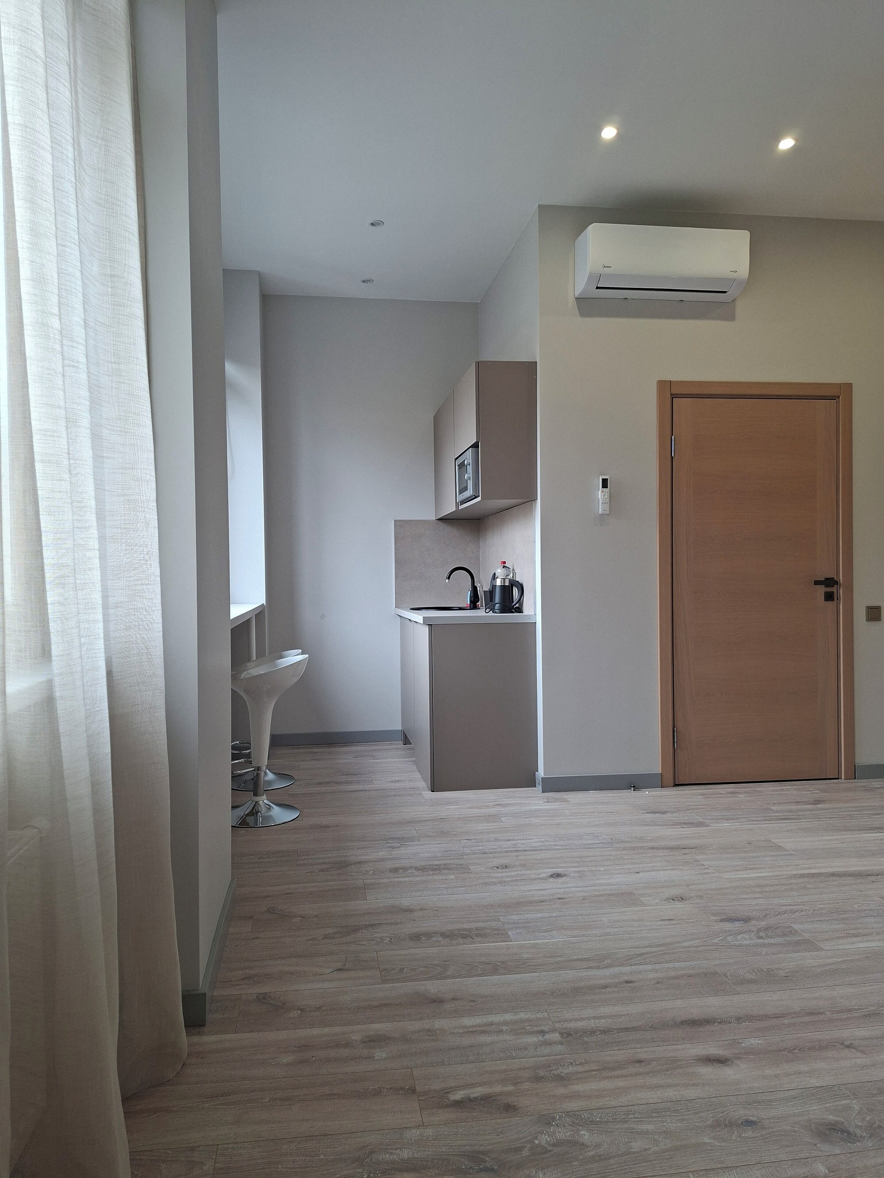 A modern kitchen with a built-in microwave, a coffee machine, and a wooden door.