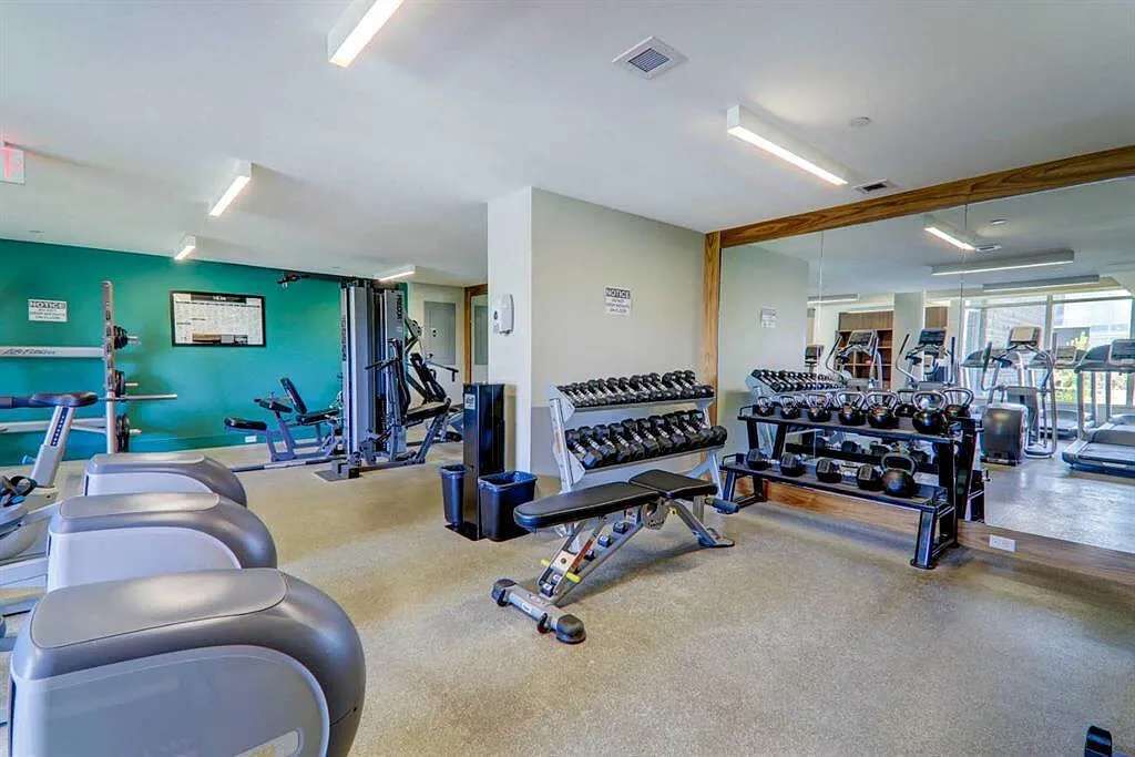 A gym with treadmills, weight machines, and a rack of dumbbells.