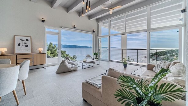 A spacious living area with a large window overlooking a scenic view, a dining area with a table and chairs, and a cozy seating area with a sofa and a coffee table.