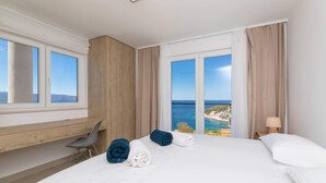 A hotel room with a large bed, a desk, and a view of the sea.