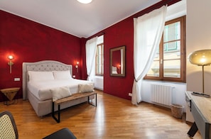 Une chambre à coucher avec un lit, une table de chevet, une lampe et une vue sur l’extérieur par une fenêtre.