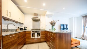 Una cocina moderna con armarios de madera, electrodomésticos de acero inoxidable y una isla central.