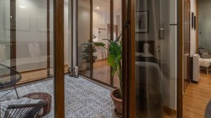 A modern living room with a glass door leading to a balcony, a potted plant, and a patterned floor. - Calma Center Granada (Granada)