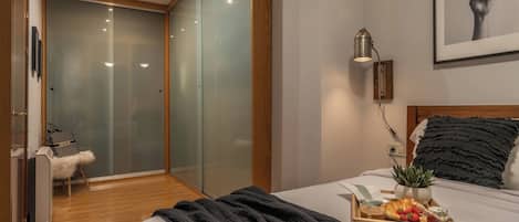 A modern bedroom with a bed, bedside table, and a tray with breakfast items.