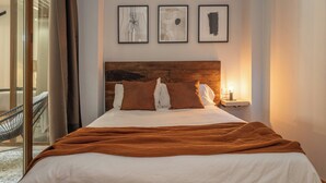 A hotel room with a bed, a nightstand with a lamp, and three framed artworks on the wall. - Cozy Home Casa Laura (Granada)