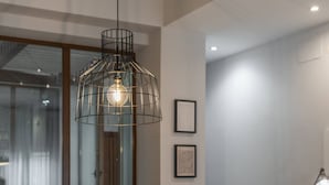 A dining area with a wooden table set for four, black chairs, a hanging light fixture, and a vase with flowers. - Cozy Home Casa Laura (Granada)