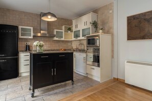 A modern kitchen with a black refrigerator, white cabinets, a microwave, and an oven.