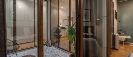 A modern interior with a glass door leading to a living area, a potted plant, and a patterned floor.