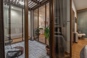 A modern interior with a glass door leading to a living area, a potted plant, and a patterned floor.