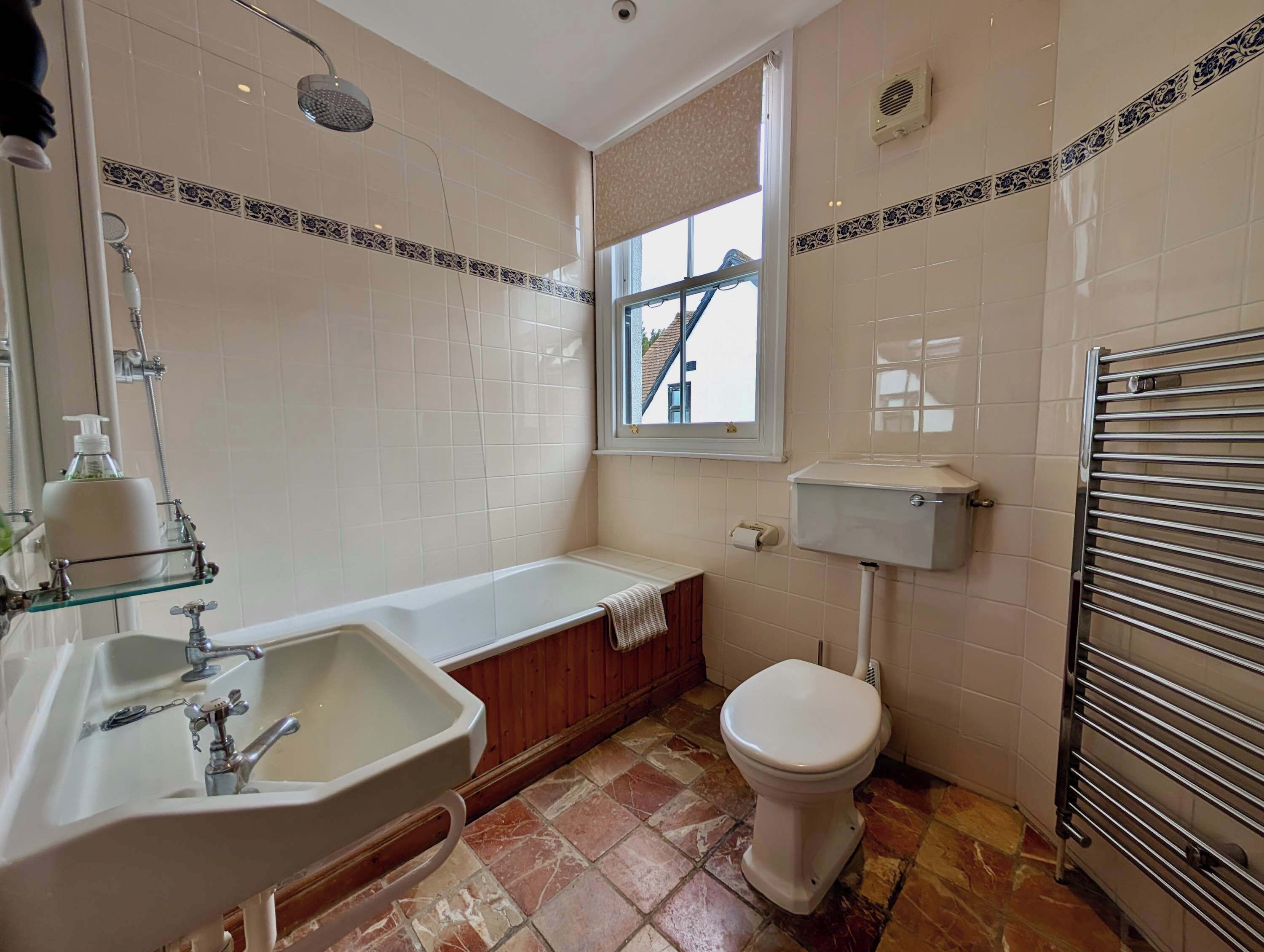 Une salle de bain avec une baignoire, des toilettes, un lavabo et une fenêtre.