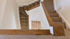 Eine Treppe mit hölzernen Geländern und Teppichstufen, die zu einem Raum mit einer weißen Tür führt.