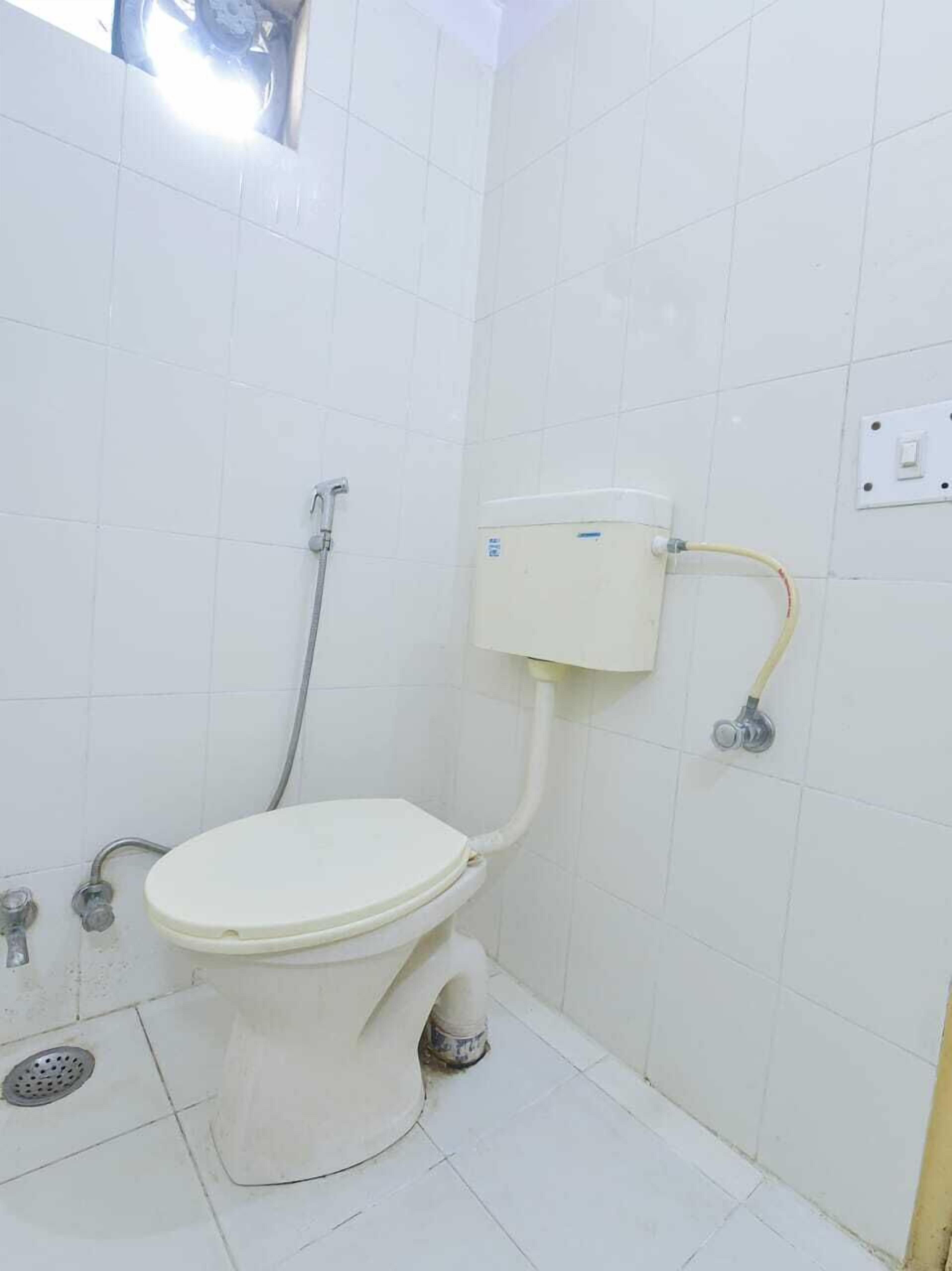 A small, white bathroom with a toilet, a shower, and a wall-mounted toilet paper holder.