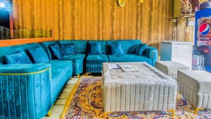 Ein Wohnzimmer mit einem türkisfarbenen Sofa, einem gemusterten Teppich und einem kleinen Tisch mit Zeitschriften.
